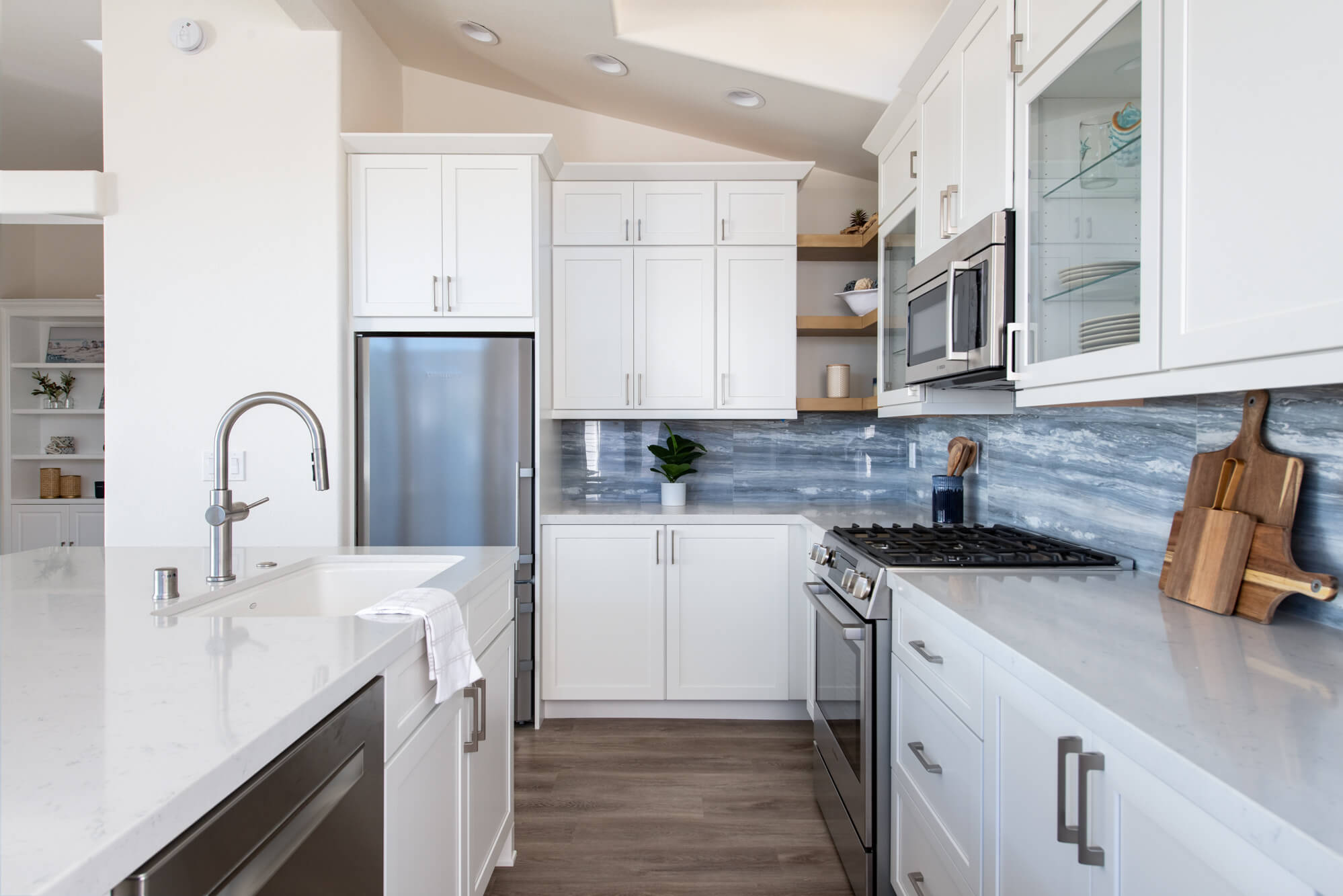Spacious-kitchen-remodel-withlarge-white-island-andwhite-cabinetry-with-glossy-blue-backsplash