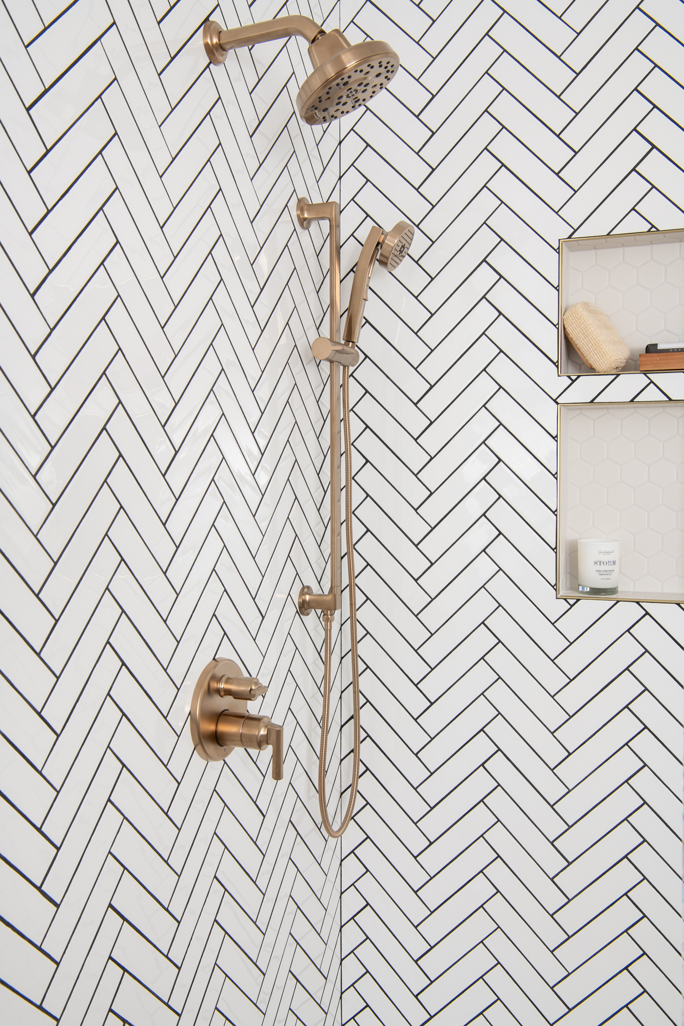 Herringbone-mosaic-series-Cognito-in-Ice-Glossy-material-Ceramic-brushed-brass-schluter-trim-black-grout-mosaic-hex-niche-and-flooring-in-white-porcelain
