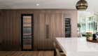 Omega-full-access-base-and-island-cabinets-in-walnut-wood-and-riverbed-finish-include-fridge-freezer-pantry-and-wine-refrigerator