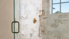 marble-shower-with-antique-brass-shower-fixtures-and-mosaic-flooring-with-linear-drain