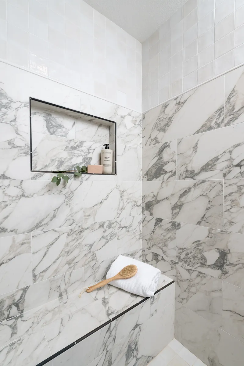 sea-pointe-design-and-remodel-shower-wall-tile-in-porcelain-carrera-arabescato-including-a-niche-and-bench-with-matte-black-trim