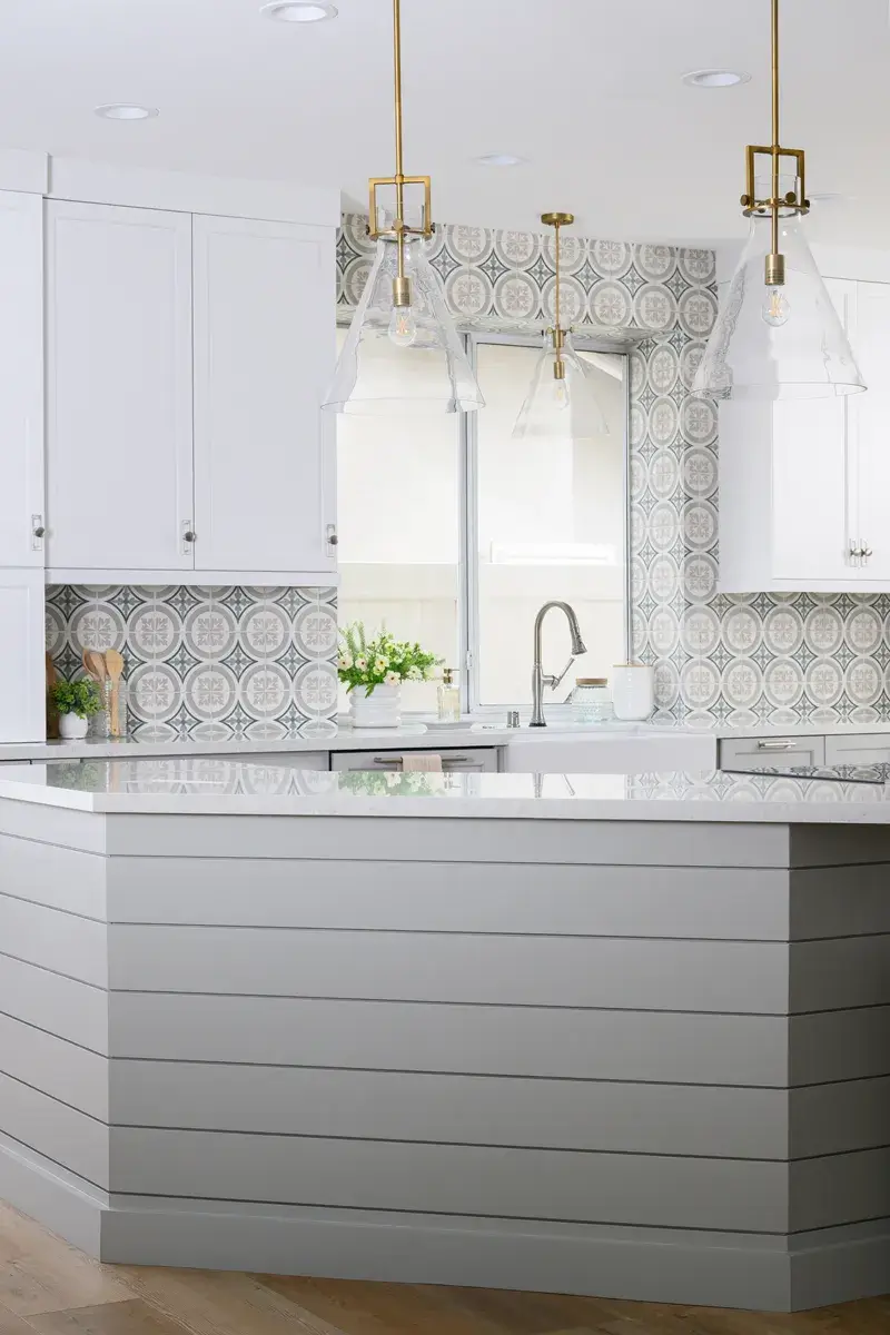 four-brushed-brass-beaker-pendants-with-clear-glass-covers-sit-above-the-massive-island