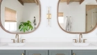 two-wood-framed-mirrors-and-two-champagne-bronze-light-wall-sconces-sit-above-the-vanity