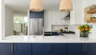 two-beaded-light-pendants-sit-over-kitchen-peninsula-with-quartz-countertops-in-Miami-Versa-finish-with-a-light-polish