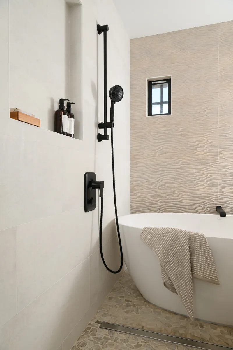 side-shower-walls-are-a-smooth-porcelain-tile-by-the-Newport-series-in-Natural-white-and-flooring-in-flat-stone-pebble-in-honed-cream