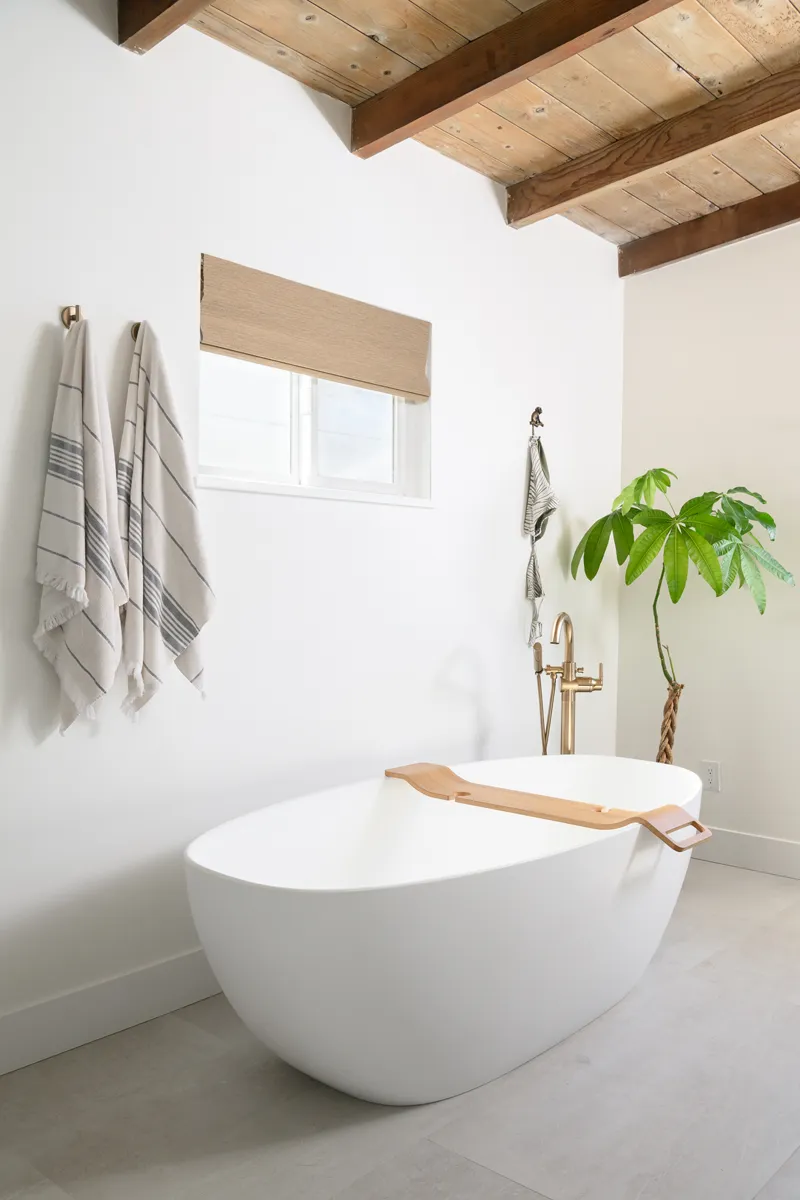 matte-white-freestanding-soaking-tub-with-single-handle-floor-mounted-tub-filler-with-handshower-in-chamapgne-bronze