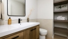 powder-bath-Kemper-cabinets-in-Natural-Oak-finish-with-polished-quartz-countertops-in-Aurum-matte-black-faucet-plus-omega-linen-closet-shelving