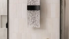 Lava-black-LED-wall-sconce-sits-on-verticle-subway-glazed-ceramic-tile-backsplash-in-cloe-glossy-white-finish
