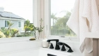 white-drop-in-bath-sits-under-large-windows-for-natural-lighting