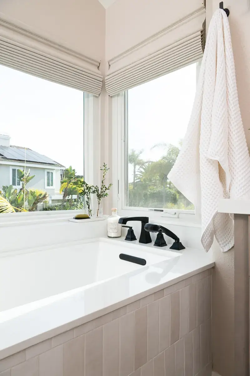 white-drop-in-bath-sits-under-large-windows-for-natural-lighting