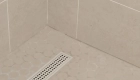 shower-pan-includes-a-linear drain-with-ceramic-floor-tiles-with-circle-design-in-Kumo-Gray-Matte-finish