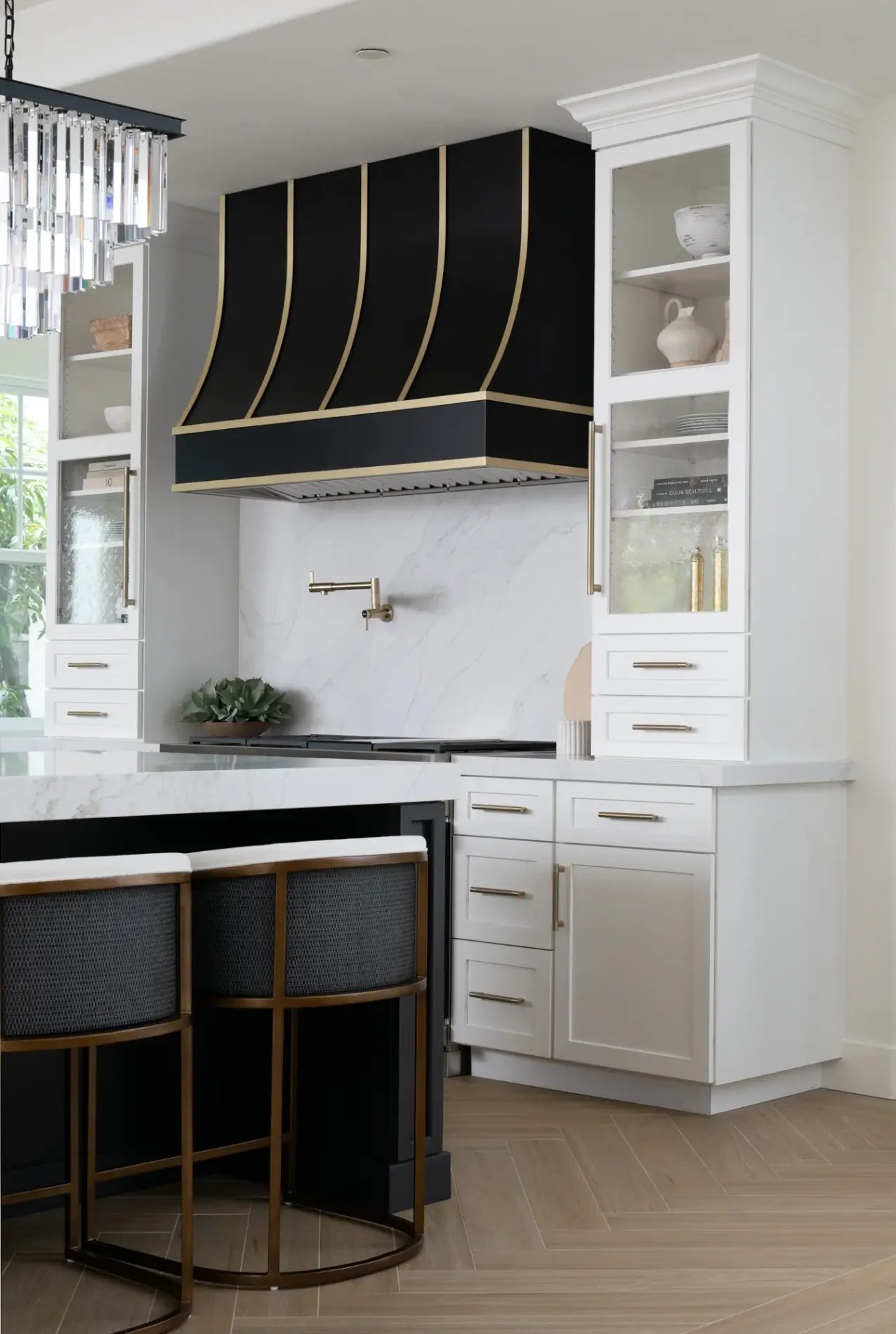 custom-sloped-appliance-hood-in-black-with-brass-strappings-sit-above-a-Wolf-range-and-satin-gold-pot-filler